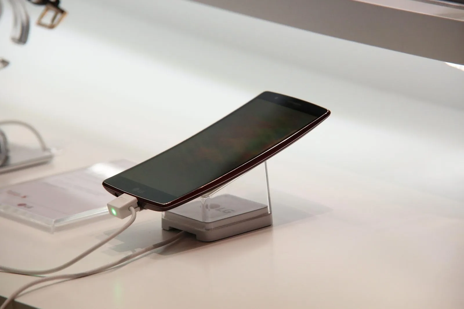 Ponsel yang sedang diisi daya dengan kabel putih di atas meja display